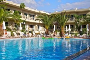 a pool at a hotel with palm trees and chairs at Solimar Ruby in Malia