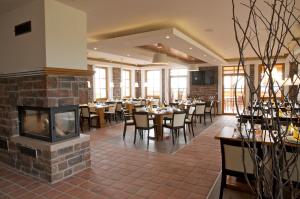 a restaurant with tables and chairs and a fireplace at Hotel Krušnohorský Dvůr in Cínovec