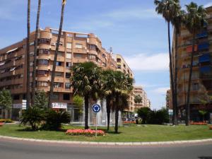 a building with palm trees in front of a street at Apartamento Cardenal Cisneros in Gandía