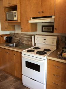 a kitchen with a white stove and a sink at Camping Le 4 Chemins in LʼAnse-Saint-Jean