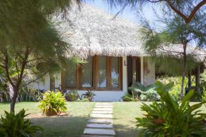 a house with a thatched roof and a yard at Refugios Parajuru - Villa Alegre in Parajuru