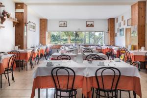 un comedor con mesas y sillas con manteles blancos en Hotel Darsena, en Passignano sul Trasimeno