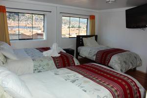 a room with two beds and a tv and windows at Hospedaje Qori Punku in Cusco