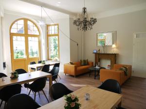 a living room with tables and chairs and a chandelier at Comfort-Hotel garni Schierker Waldperle - inklusive Wellness in Schierke