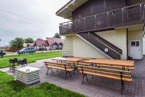 a patio with benches and tables in front of a house at Apartamentai Trys pušys in Šventoji
