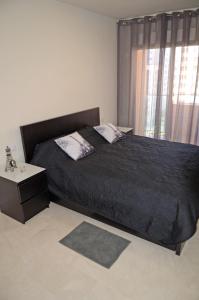ein Schlafzimmer mit einem Bett mit einer schwarzen Bettdecke und einem Fenster in der Unterkunft Apartment Sincera in Benidorm