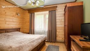 Un dormitorio con una cama y un escritorio con televisión. en Goryanka, en Yaremche 83 fotos más
