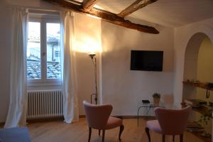 un soggiorno con sedie, TV e finestra di Elegante Luminoso Attico Centralissimo a Siena