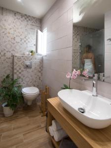 a bathroom with a sink and a woman in the mirror at Riaki Apts in Malia