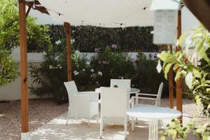 een patio met witte tafels, stoelen en bloemen bij Apartamentos Casa Torres - Adults Only in Albir