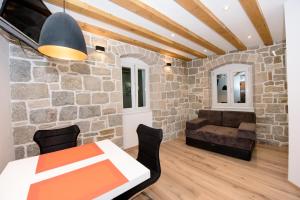 sala de estar con pared de piedra, mesa y sillas en Lucy in Centre Apartment en Split