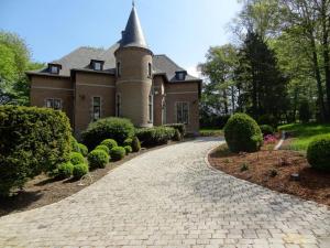 a brick driveway leading to a house with a turret at Le chateau des eglantines in Montignies-le-Tilleul