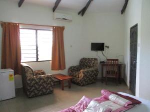 a living room with a couch and a chair and a television at Paradise Ocean Resort in Cape Coast