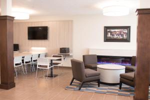 una sala de espera con sillas, mesas y TV en Microtel Inn & Suites by Wyndham Springville en Springville