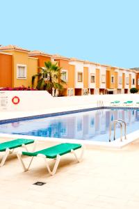 una piscina con due sedie accanto a un edificio di Sunset View And Pool In Paradise ad Adeje