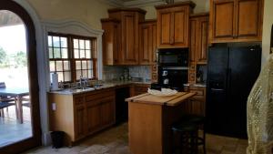 a kitchen with wooden cabinets and a black refrigerator at Thorn Hill Vineyards Villa Suites in Clear Lake Riviera
