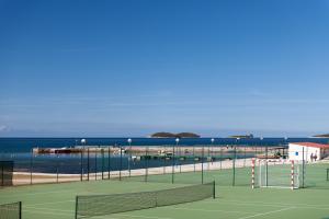 um campo de ténis com o oceano ao fundo em Maistra Select Villas Rubin Resort em Rovinj