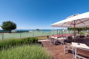 a deck with tables and chairs and a tennis court at Maistra Select Villas Rubin Resort in Rovinj