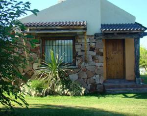 a stone house with a door and a plant in front at Establecimiento Rural El Chañar in San Rafael