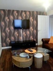 a living room with a table and a television on a wall at Falconwood Apartment in Manchester