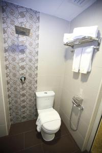 a bathroom with a toilet and towels on a wall at Al Khatiri Hotel in Kubang Kerian