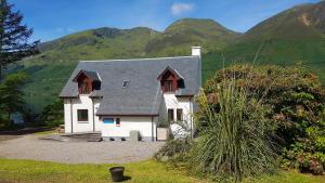 a white house with mountains in the background at Letterfinlay Lodge House in Letterfinlay