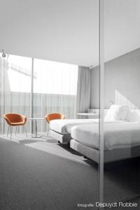 a bedroom with two beds and a table and chairs at D-Hotel in Kortrijk