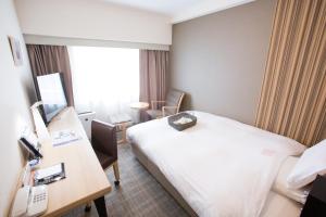 富山市にある富山地鉄ホテルのベッドとデスクが備わるホテルルームです。