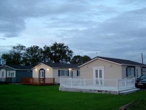 une petite maison avec une terrasse couverte sur une pelouse dans l'établissement Warrens Village Motel and Self Catering, à Clevedon