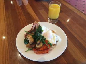 a plate of food with eggs and mushrooms and a glass of orange juice at Bell Tower Inn in Ballarat