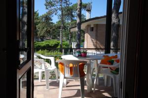 - une table et des chaises blanches sur la terrasse dans l'établissement Villaggio Alex, à Lignano Sabbiadoro