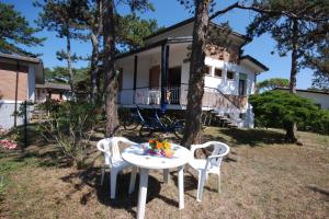 une table et des chaises devant une maison dans l'établissement Villaggio Alex, à Lignano Sabbiadoro