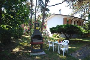 - un barbecue dans une cour avec une table et des chaises dans l'établissement Villaggio Alex, à Lignano Sabbiadoro