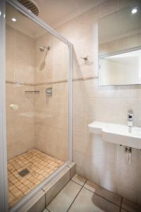 uma casa de banho com um chuveiro e um lavatório. em Santorini Guesthouse em East London