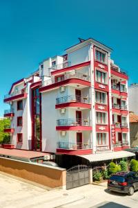 a red and white building with a car parked in front at Family Hotel Prestige in Burgas