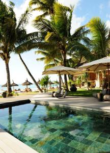 a swimming pool with umbrellas and palm trees at Constance Sakoa Boutik in Trou aux Biches