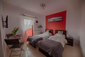 a bedroom with two beds and a red wall at 4 strony świata in Jarosławiec