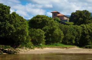 a house sitting on top of a hill next to a river at Hotel Villa Miramar in Po
