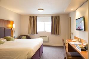 una camera d'albergo con due letti, una scrivania e una finestra di Hello Hotel a Manchester
