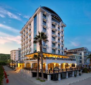 un grande edificio bianco con palme di fronte di Ayvalik Cinar Hotel a Ayvalık