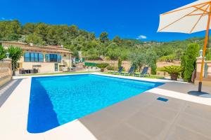 a villa with a swimming pool and an umbrella at Sa Tanca -Mancorina- in Mancor del Valle