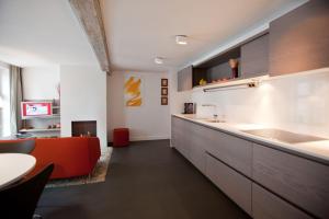 a kitchen with an orange couch and a table at Drabstraat 2 Apartment in Ghent