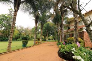 een huis met palmbomen en bloemen ervoor bij Hillside Manor in Bulawayo