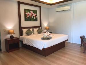 a bedroom with a bed with white sheets and flowers on it at The Hip Resort @ Khao Lak in Bang Sak