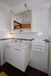 a white bathroom with a sink and a mirror at Apartment Palma in Bibinje