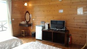 仁愛鄉的住宿－清境小太陽景觀木屋 ，一间卧室设有木墙、电视和冰箱。