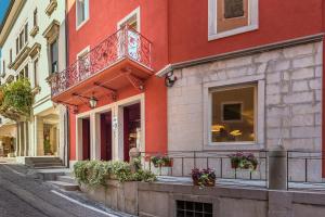 a red building with a balcony on a street at Hotel San Daniele in San Daniele del Friuli
