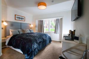 um quarto com uma cama grande e uma televisão em Black Bull Inn, Moffat em Moffat