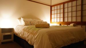 a bedroom with a white bed with a window at Harmony House Hakuba in Hakuba +10 photos