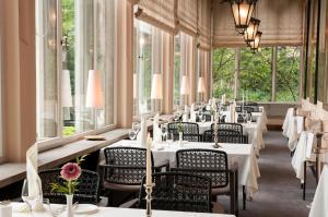 a restaurant with white tables and chairs and windows at Hotel Schloss Eckberg in Dresden